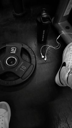 a pair of white sneakers sitting on top of a black floor next to an electronic device