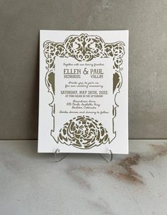 a wedding card with an ornate design on it, sitting on a marble countertop