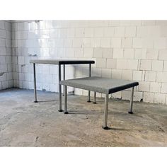 two tables sitting next to each other in front of a white brick wall and floor