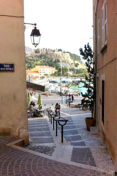 an alley way with steps leading up to the street and people sitting at tables on either side