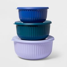 three bowls stacked on top of each other in different colors and sizes, one with a blue lid