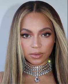 a close up of a woman with blonde hair and jewelry on her neck, looking at the camera