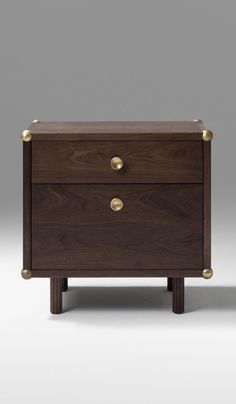 a wooden chest with two drawers and brass pulls on the front, against a gray background