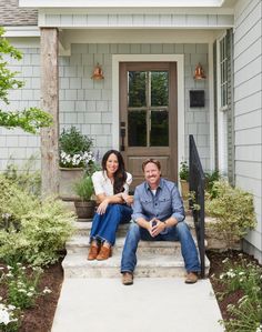 a man and woman sitting on steps in front of a house