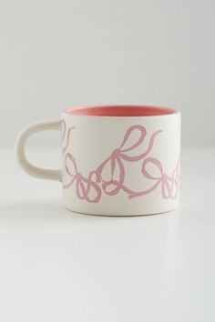 a pink and white coffee cup sitting on top of a table