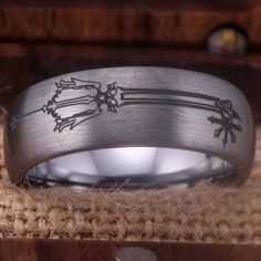 a wedding ring with an arrow design on it sitting in a wooden box, surrounded by burlies