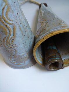 two ceramic vases sitting next to each other on a white counter top, one is broken and the other has been left open