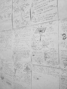 a wall covered in lots of paper with writing and diagrams on it's sides