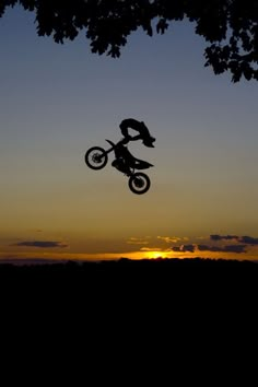 a person on a dirt bike doing a trick in the air at sunset or dawn