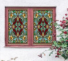 two stained glass windows with decorative designs on the side of a building in front of some plants