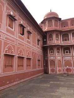 an old building with many windows and arches on the outside wall is painted pink in color