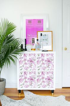 a white cabinet with flowers painted on it and a potted plant next to it