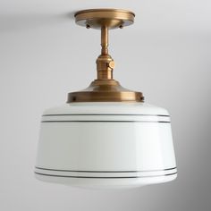 a white and gold light hanging from a ceiling fixture with a black stripe on the bottom