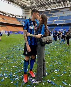 a man and woman kissing on the field at a soccer game