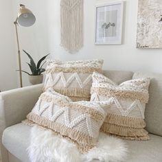 some pillows on a couch in a room with white walls and pictures hanging above them