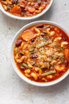 two bowls of pasta and vegetable soup on a table