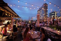 many people are sitting at tables outside in the evening