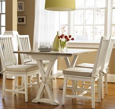 a dining room table with four chairs and a vase on the table next to it