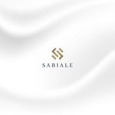 the logo for sabiane is shown in gold on a white silk background with wavy folds