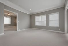 an empty living room with two windows and no curtains on the walls, is shown in this image