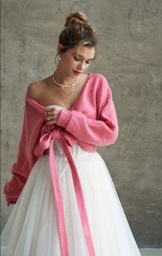 a woman wearing a pink sweater and white tulle skirt