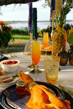 an outdoor table set with food and drinks