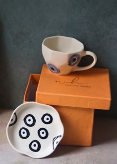 two bowls with eyes painted on them are sitting in front of a box that is open