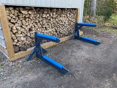 there is a pile of firewood in the back of a building with blue legs