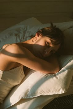 a woman laying on top of a white pillow