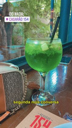 a green drink sitting on top of a table next to a purse