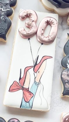 cookies decorated with icing and decorations on a counter top, including an image of a woman holding a balloon