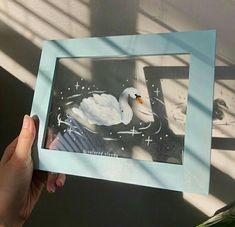 a person holding up a photo with a swan on it