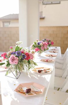 the table is set with pink and purple flowers