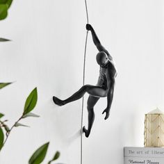 a statue of a man climbing up the side of a wall with a rope attached to it