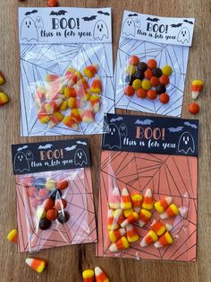 four bags of halloween candy sitting on top of a wooden table