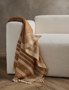 a brown and white blanket sitting on top of a wooden floor next to a couch