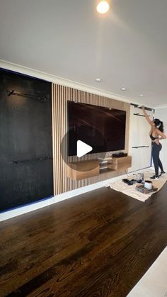 a woman standing in front of a tv on top of a hard wood floor next to a blackboard