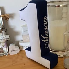 a candle and some other items on a wooden table next to a glass vase with the word mom written on it