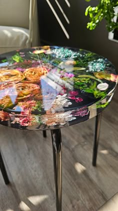 a table with flowers painted on it in front of a chair and potted plant