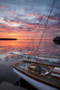 a sailboat is docked in the water at sunset