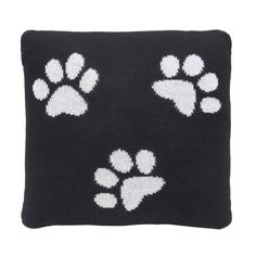 a black pillow with white paw prints on the front and back, it is knitted in