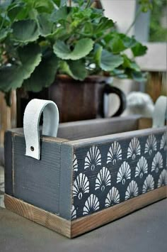 a wooden box sitting on top of a table next to a potted plant