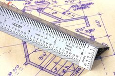 a ruler sitting on top of a piece of paper with blueprints in the background