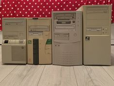 several old computers are lined up in front of a red polka dot bed spread on the floor