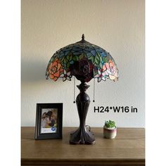 the lamp is next to a potted plant and a picture frame on a table