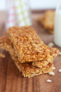 three granola bars sitting on top of a wooden table next to a glass of milk