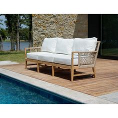 a couch sitting on top of a wooden deck next to a swimming pool with water