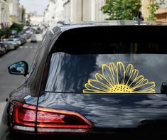 a flower sticker is on the back of a black car in front of a row of parked cars