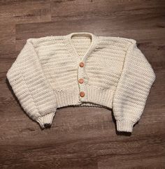 a white sweater sitting on top of a wooden floor