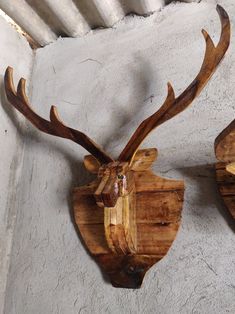 two wooden deer head mounted to the side of a wall next to a white stucco wall